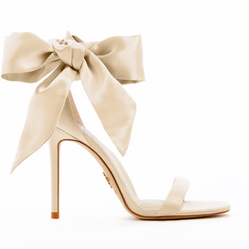 Elegant gold high-heeled vegan sandal, featuring a statement vegan silk-satin bow, sleek ankle strap, and minimalist open-toe design, perfect for sophisticated and stylish occasions.